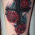 Tatuaje en el antebrazo,
cruz grande negro con rosas de color rojo oscuro