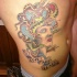 Old cartoon style painted colored Medusa head tattoo on side with lettering