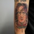 Old school style colored arm tattoo of Lennon face with dragonfly