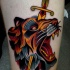 Old school style colored thigh tattoo of lion head with dagger