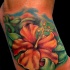 fiore ibisco arancione tatuaggio sul piede