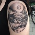 Oval shaped black ink shoulder tattoo of night tree with mountains