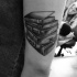 Tatuaje en el brazo, pila de libros gruesos negros blancos