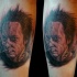 Portrait style colored creepy man face tattoo on leg