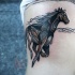 Tatuaggio realistico sul fianco il cavallo nero che galoppa