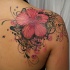 Tatuaje de hibisco hawaiano precioso con rizos bonitos negros