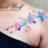 Rainbow colored stars with paint drips tattoo on chest and shoulder by Javi Wolf in watercolor style
