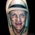 Tatuaje en el brazo, retrato realista de actor famoso sonriente