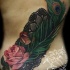 Realism style amazing looking colored back tattoo of rose flower with peacock feather