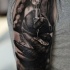 Realism style black ink shoulder tattoo of hand with tattoo machine