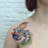 Realism style colored cat face with little bird tattoo on shoulder