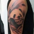 Realism style colored shoulder tattoo of panda bear with bamboo