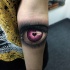 Realism style colored woman eye stylized with small black heart forearm tattoo