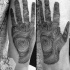 Realistic looking black ink arm tattoo of human hand with prints