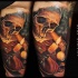 Realistic style colored human skull tattoo on arm combined with burning candle