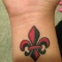 rosso nero fleur de lis tatuaggio sul polso