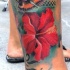 fiore ibisco rosso con farfalla tatuaggio sulla gamba