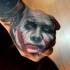 Sharp designed colored sad Joker face tattoo on fist