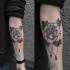 Tatuaje en el antebrazo,
rosa simple con colgante, colores negro blanco