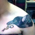 Tatuaje en el hombro,
 cuervo con tijeras en el pico