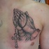 Tatuaje en el pecho, 
manos que oran de un hombre religioso