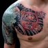Simple old school style chest tattoo of daruma doll with flowers and waves