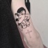 Small black ink arm tattoo of woman with red cross