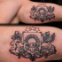 Small black ink biceps tattoo of ancient emblem