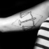 Small black ink biceps tattoo of libra with rhombus