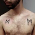 Small black ink chest tattoo of interesting symbols