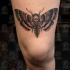 Small black ink thigh tattoo of butterfly with human skull