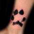 Small black ink wrist tattoo of animal paw
