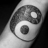 Kleines schwarzes Yin-Yang Symbol Tattoo mit ornamentalen Blumen