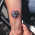 Small circle shaped wrist tattoo Earth planet