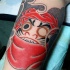 Small illustrative style biceps tattoo of daruma doll
