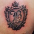 Small shield shaped chest tattoo of old symbol with lettering
