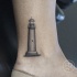 Tatuaje pequeño en el tobillo, 
faro gris simple