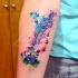 Small watercolor style little ink pot with feather and cat paw prints tattoo on forearm