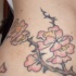 Tatuaje en la cadera, rama espinosa con flores de color rosa
