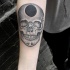 Stippling style black and white forearm tattoo of skull with black whole