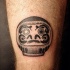 Stippling style black ink biceps tattoo of daruma doll head