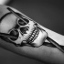 Stippling style black ink forearm tattoo of human skull with drum sticks