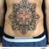 Stippling style colored belly tattoo of Hinduism flower