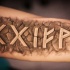 Stone like black ink arm tattoo of ancient lettering