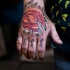 Strange designed red colored glowing rose tattoo on hand with lettering