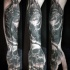Strange looking black ink human skull tattoo on hand combined with rhino on forearm
