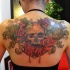 Stunning looking colored whole back tattoo of human skull and flowers