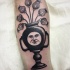Surrealism style black ink arm tattoo of funny vase with flowers and face