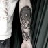 Surrealism style black ink forearm tattoo of human face with mask and skull
