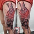 Surrealism style colored thigh tattoo of human hand with people and lettering